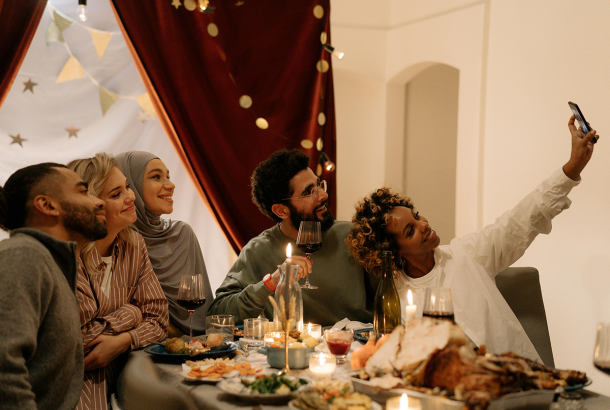 A diverse group of friends eating together and taking a selfie.