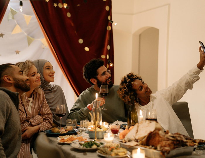 A diverse group of friends eating together and taking a selfie.