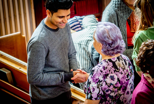 Two people smiling and shaking hands at church